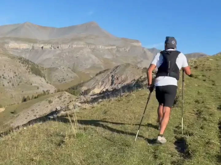 Randonneur avec bâtons sur un sentier de crête en montagne, en préparation randonnée avec BFT Coaching